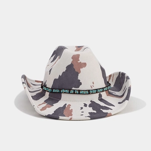 Detail of western cow print cowboy hat featuring ethnic beaded band and turquoise accents