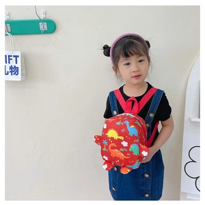 Detail of red kids dinosaur backpack with adjustable straps worn by a little girl
