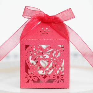 Detail of red laser-cut wedding favor box with heart patterns and organza ribbon