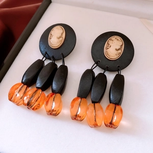 Macro shot of vintage portrait relief earrings with wood beads and amber resin pendants