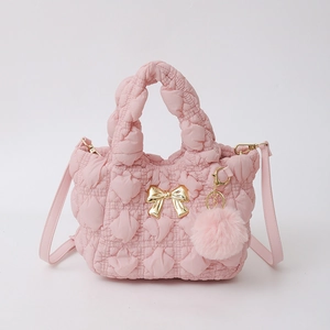 Vue détaillée du sac à main en nylon rose matelassé avec nœud doré et pompon en peluche