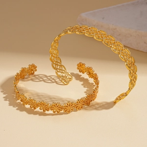 Detailed close-up of golden hollowed flower and lattice patterns on open cuff bracelets
