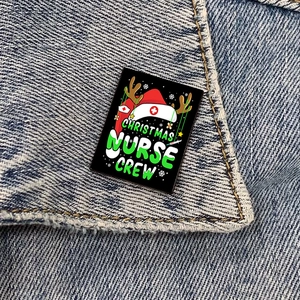 Christmas Nurse Crew enamel badge pinned on a denim jacket collar in a close-up view