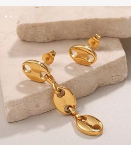 Detail of gold geometric pig nose earrings on textured stone base in high quality macro view