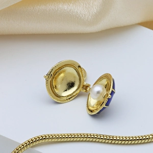 Golden shell pendant with deep blue enamel and white pearl on satin background