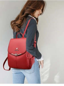 Detail view of red leather backpack with heart buckle and kangaroo metal logo on model