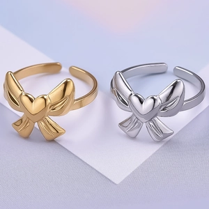 Détail de bagues papillon ajustables en finitions or et argent sur fond bleu clair