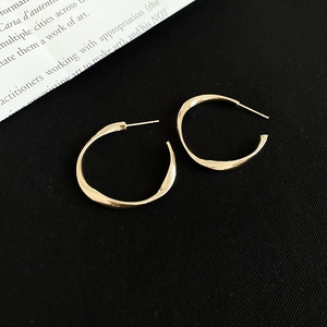 Detailed view of twisted gold-finished hoop earrings with smooth metallic texture