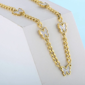 Close-up of golden NK chain necklace featuring white shell butterfly charms on white stone
