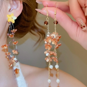 Detail of floral tassel earrings with orange resin flowers and white pearls drops