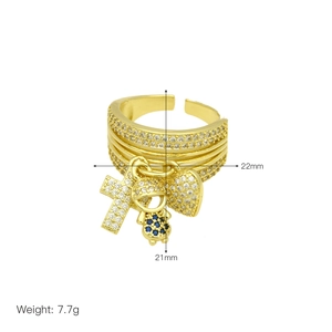 Detail view of gold ring with cross and heart charms featuring cz stones and blue gems