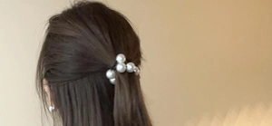 Detail showing white pearls on a black elastic hair tie worn on a woman's hair