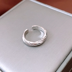 Macro shot of silver twisted ring with zircon pavé detail on a gray textured surface