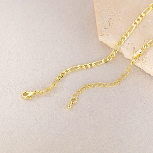 Close-up of gold Figaro chain with lobster clasp and adjustable extension chain link