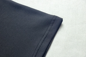 Detail of dark grey knit dress featuring high-quality double-needle stitching on the hem