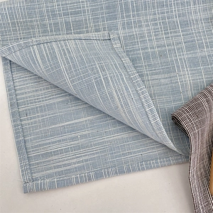 Detail of light blue checkered placemat with fine woven texture and reinforced stitching