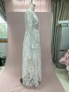 Detailed view of delicate white floral lace embroidery and sheer long sleeves on the dress