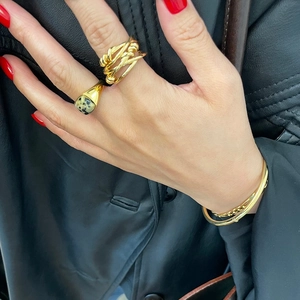 Close-up of woven gold 925 silver ring and spotted stone ring paired with bracelets