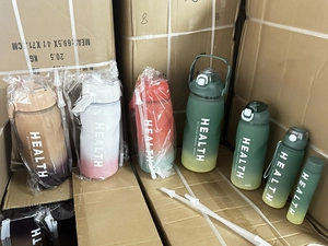 Bulk set of gradient water bottles with health slogans in warehouse shipping boxes