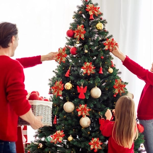 Family decorating Christmas tree with red glitter poinsettia and gold bell ornaments