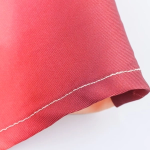 Detalle de vestido midi de satén rojo con textura de sarga fina y costura blanca precisa