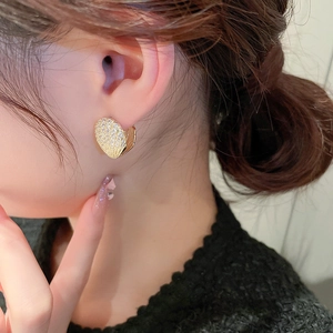 Elegant gold-plated heart stud earrings with zircon crystals shown on a female model