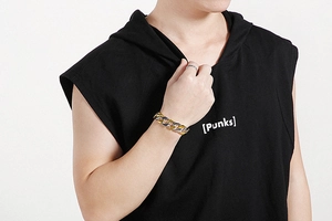 Detail of two-tone gold and silver Cuban link chain bracelet on a male model's wrist