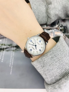Elegant ladies' watch with white dial, blue Roman numerals and brown leather strap on wrist