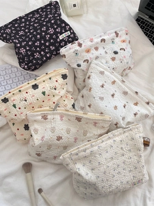 Quilted floral and animal print cosmetic bags stacked with makeup accessories