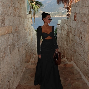 Detail of elegant black long sleeve cutout dress on a scenic Mediterranean coastal background