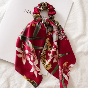 Detail of satin ponytail scrunchie with leopard print and burgundy floral streamers