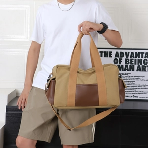 Men's khaki canvas and brown leather travel tote bag with adjustable shoulder strap