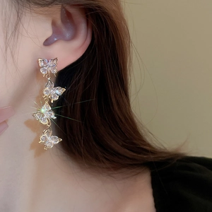 Close-up of sparkling zircon butterfly long tassel earrings on a model with starburst effect