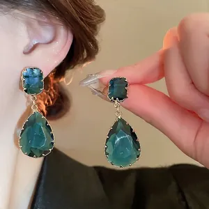 Elegant emerald green teardrop and square gemstone earrings with gold-toned metal borders