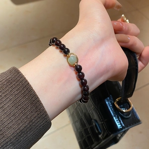 Detail of red garnet beaded bracelet with green jade charm on model wrist