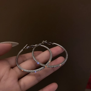 Eleganti orecchini a cerchio geometrici in argento con zirconi bianchi tenuti in mano