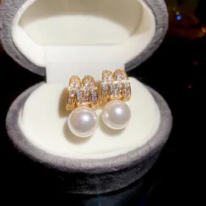 Elegant gold letter M earrings featuring zircon pavé and dangling white round pearls