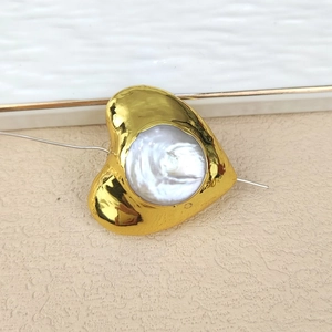 Detail of heart-shaped gold plated bead with white pearl inlay for DIY jewelry design