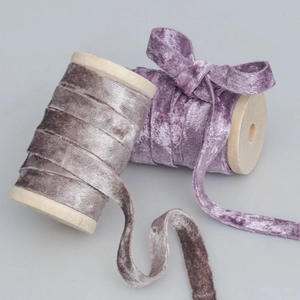 Macro view of velvet ribbon rolls in grey and lilac purple on wooden spools