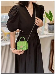 Close-up of green quilted jelly bag with metal chain strap in casual setting