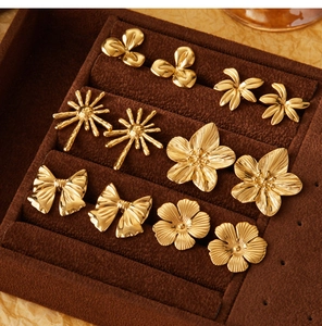 Collection of golden floral and bow earrings on brown velvet display tray
