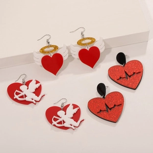 Macro shot of red acrylic heart earrings featuring angel wings and cupid silhouettes