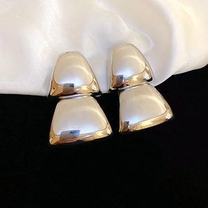 Macro shot of polished silver geometric trapezoid earrings on silk and velvet background