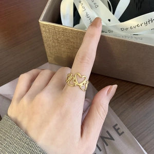 Détail d'une large bague cœur ajourée plaquée or 18 carats portée au doigt