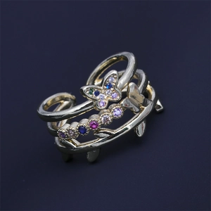 Bague ajustable papillon dorée avec zircons colorés sur fond bleu foncé