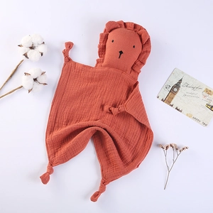 Detail of soft terracotta cotton muslin baby comforter with a cute lion head and knotted corners
