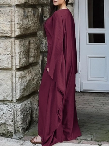 Détail d'une robe longue bordeaux élégante avec texture plissée et manches cape