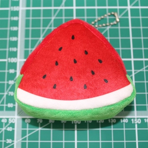Triangle plush watermelon coin purse with silver chain keychain on a grid background