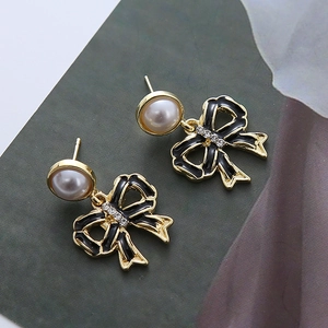 Détail macro de boucles d'oreilles papillon en émail noir élégant et perles de culture