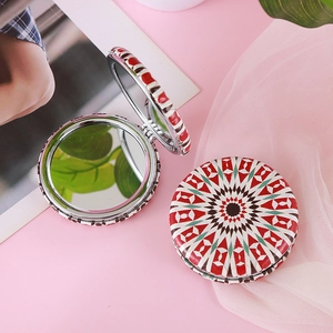 Detail of round portable makeup mirrors with bohemian geometric patterns on pink background